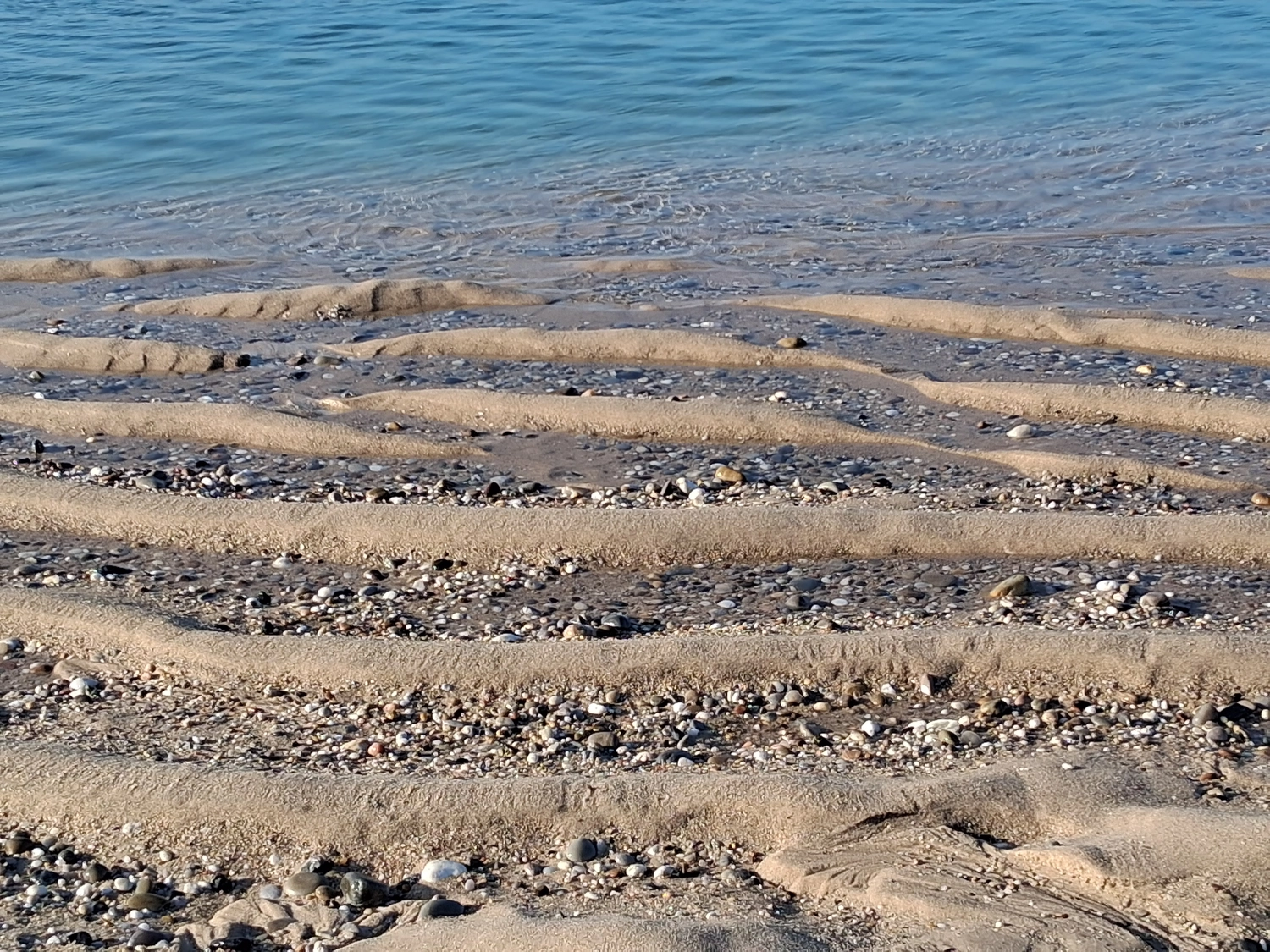 Hebamme Trauma-Fachberaterin - Coaching, Beratung, Kurse und Lesungen - Eine natürliche Küstenlandschaft, in der Wasser über ein Bett aus Sand und Kieselsteinen fließt.