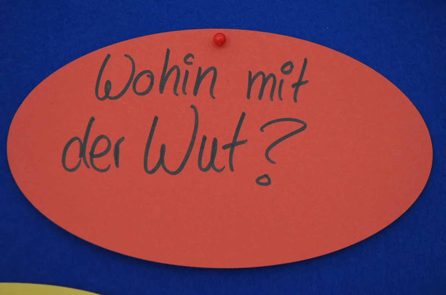 Hebamme Trauma-Fachberaterin - Coaching, Beratung, Kurse und Lesungen - Auf einer orangefarbenen, ovalen Karte, die auf einem blauen Hintergrund befestigt ist, steht in schwarzer Tinte die handgeschriebene deutsche Frage „Wohin mit der Wut?“.