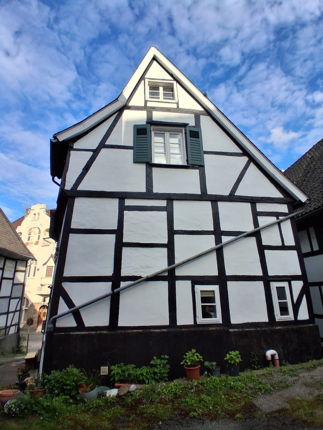 Hebamme Trauma-Fachberaterin - Coaching, Beratung, Kurse und Lesungen - Ein charmantes, schwarz-weißes Fachwerkhaus mit grünen Fensterläden und einem Blumengarten im Vordergrund.